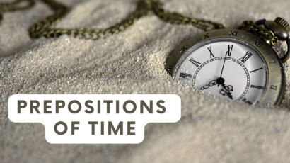 a watch in sand showing the time 3:35 a and the text prepositions of time