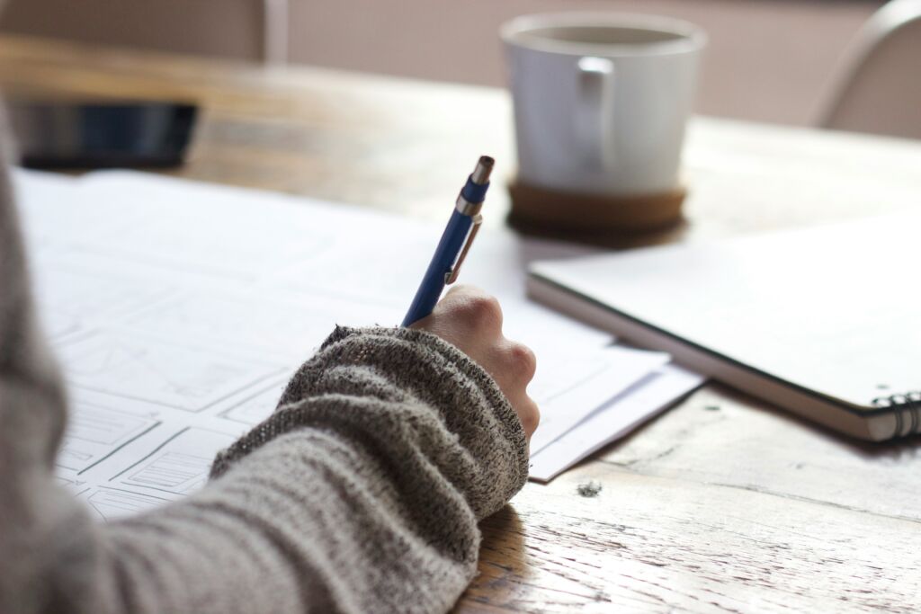 a man studying english gerunds with his papers all over the table along with a cup of coffee